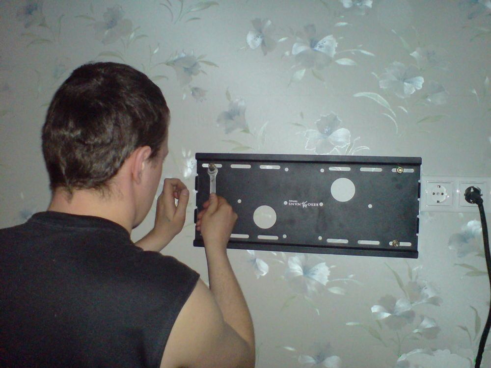 Чоловік встановлює кронштейн для телевізора на стіну